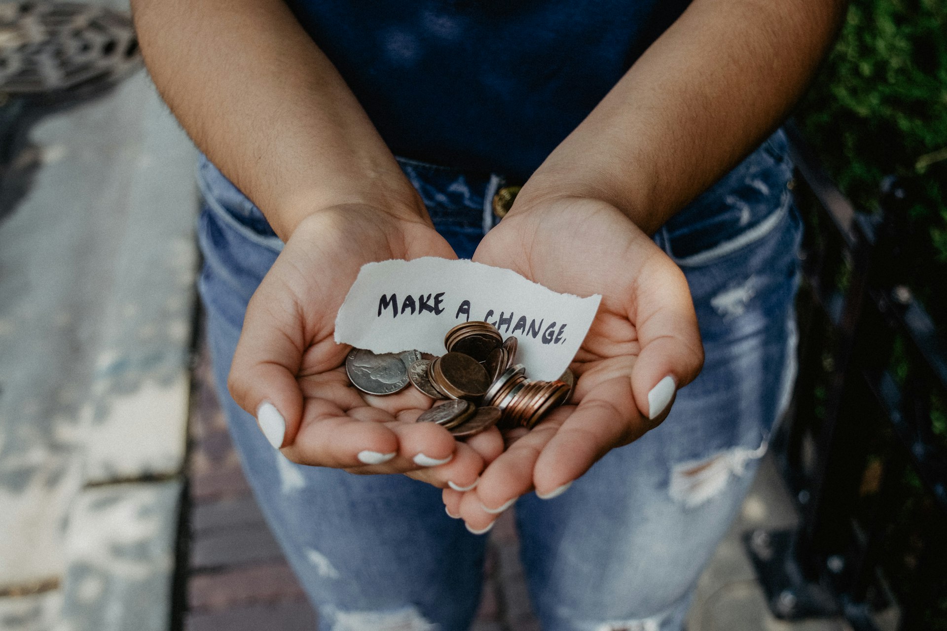 Open hands holding coins with a torn 'make a change' note