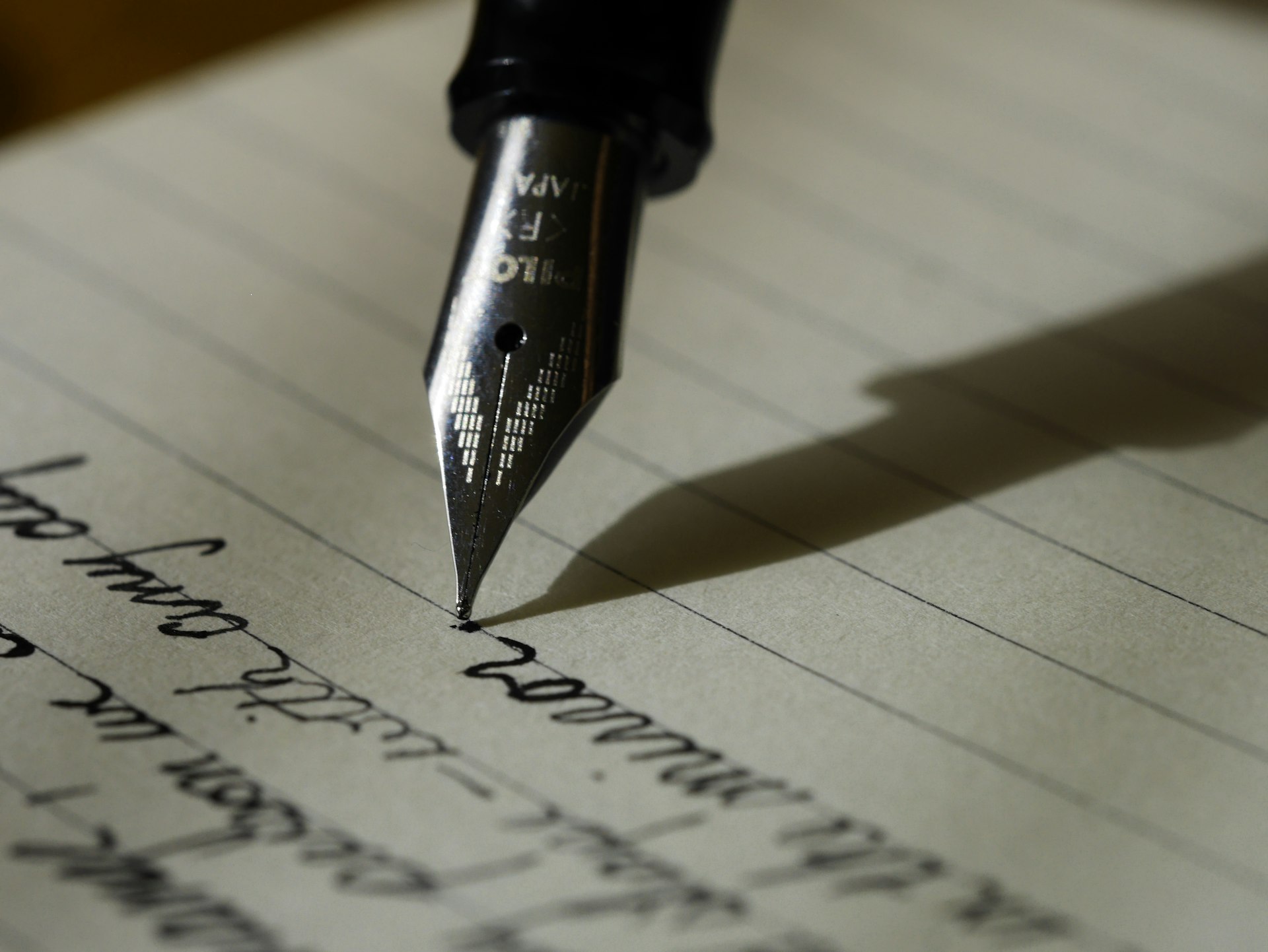 A fountain pen writing in cursive on lined paper